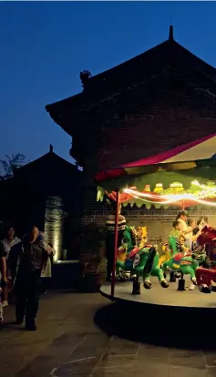  ??  ?? Children playing on a merry-go-round in the ancient city in the evening.