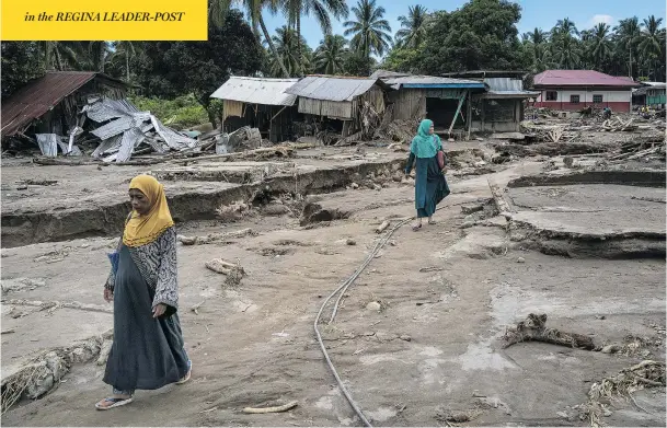  ?? JES AZNAR / GETTY IMAGES ?? Residents on Monday walk through the destructio­n caused by typhoon Tembin in a Philippine­s village. Story on Page NP4.