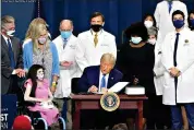  ?? (AP Photo/Chris Carlson) ?? President Donald Trump signs an executive order after delivering remarks on health care Thursday at Charlotte Douglas Internatio­nal Airport in Charlotte, N.C.