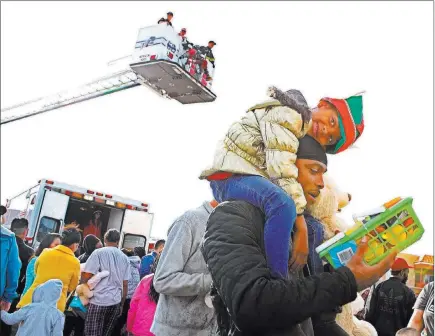  ?? Ronda Churchill ?? Las Vegas Review-journal Leilea Morrison, 5, hugs father Ladarius Morrison, who holds Leila’s gifts she received Sunday in North Las Vegas. North Las Vegas Fire Department emergency vehicles arrived with sirens blazing at Desert Palms Apartments to...