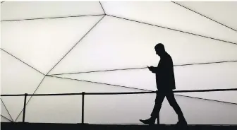  ?? THE CANADIAN PRESS ?? A man looks at his phone while walking in Barcelona, Spain. A mental-health expert suggests limiting time on social media, where misinforma­tion can run wild and lead to despair during the pandemic.