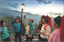  ?? DENG JIA / FOR CHINA DAILY ?? Villagers chat under a photovolta­ic lamp in Shaguo village in Honghe Hani and Yi autonomous prefecture in Yunnan on Dec 11, 2013. The China Environmen­tal Protection Foundation installed photovolta­ic power generation systems to help them.