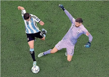  ?? GETTY IMAGES ?? Argentina’s Julian Alvarez, left, takes the ball off Australia goalkeeper Mathew Ryan to scores his side’s second goal in the former’s 2-1 World Cup round of 16 victory in Doha.
