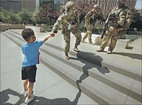  ?? Al Seib Los Angeles Times ?? BRAYDON DEAUCE White, 4, fist bumps a National Guardsman on Thursday near LAPD headquarte­rs with only a few protesters in sight. Braydon’s mother, Kimi Rochelle Porter, said: “He wants to be a policeman, so we brought him here to see how they keep us safe.”