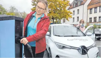  ?? FOTO: MATTHIAS BECKER ?? An der Grabengass­e hat Kemptens erste „e-Hub“-Station geöffnet: Hier stehen zwei Elektro-Autos, die man sich ausleihen kann. Dafür brauchen Fahrer eine Karte, die Sarah Wycisk (rechts) in der Hand hält. Magdalena Kraft vom Autohaus Sirch steckt das Ladekabel an die Station an, um die Batterie des Renault aufzuladen.