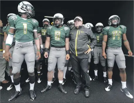  ?? Steve Dykes Getty Images ?? CHIP KELLY, center right, and his Oregon players wait to be introduced before a game against Utah in 2009. The Ducks’ attack was based on breakneck pace, which meant squeezing 80 plays into each game and no time for huddles or standing around at the...