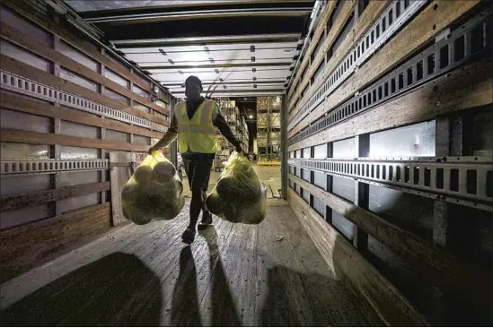  ?? Irfan Khan Los Angeles Times ?? JESUS CARRILLO loads basketball­s to be distribute­d with meal bags to children at an L.A. Unified School District procuremen­t services center in Pico Rivera.