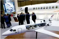  ?? — Reuters ?? Visitors stand next to a Falcon 8X aircraft replica at the Dassault Aviation booth during the European Business Aviation Convention and Exhibition in Geneva.