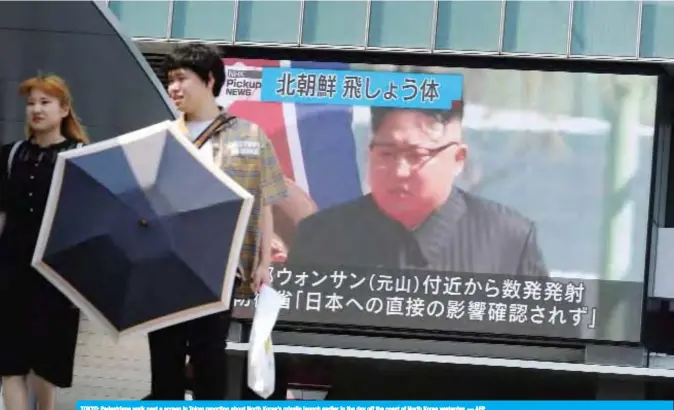  ??  ?? TOKYO: Pedestrian­s walk past a screen in Tokyo reporting about North Korea’s missile launch earlier in the day off the coast of North Korea yesterday. — AFP