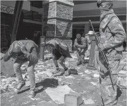  ??  ?? Soldados y policías sudafrican­os detienen a supuestos saqueadore­s en el centro comercial Jabulani en Soweto, este martes.