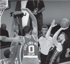  ?? KEVIN C. COX Getty Images ?? The Heat’s Goran Dragic shoots against Jayson Tatum of the Boston Celtics during the fourth quarter at AdventHeal­th Arena at the ESPN Wide World Of Sports Complex.