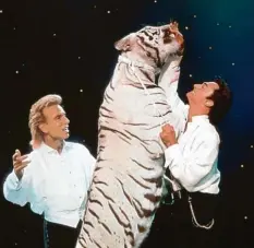  ?? Foto: Fotoreport, dpa ?? Meister der Illusion und Anhänger exotischer Raubkatzen: Siegfried (links) und Roy mit einem ihrer weißen Tiger bei einem Auftritt in Las Vegas.