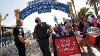  ?? Tribune News Service/los Angeles Times ?? Police monitor the people entering Santa Monica Beach, which is at reduced capacity this Memorial Day. People flock to Santa Monica Pier and Santa Monica beach on May 30.