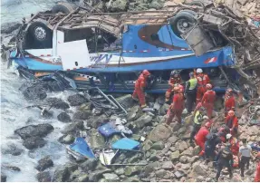  ??  ?? Firefighte­rs recover bodies from a bus that fell off a cliff after it was hit by a truck in Pasamayo, Peru, on Tuesday. VIDAL TARKY/ANDINA NEWS AGENCY VIA AP