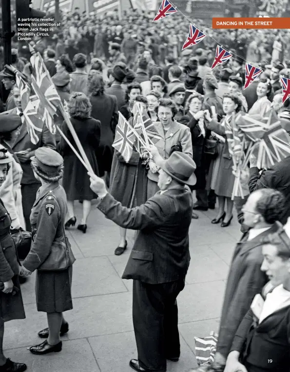  ??  ?? A partriotic reveller waving his collection of Union Jack flags in Piccadilly Circus, London