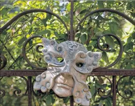  ??  ?? A mask hangs on the rusty metal gate that leads into Jennifer Myers’ garden.