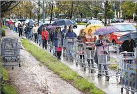  ?? Mel Melcon Los Angeles Times ?? SHOPPERS form a line to enter a Costco store in Woodland Hills on Friday.