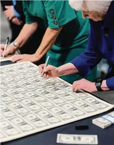  ?? Adam Perez/New York Times ?? Treasury Secretary Janet Yellen signs currency Thursday at the Bureau of Engraving in Fort Worth. Yellen, the first female Treasury secretary, and Marilynn Malerba, the first Native American to be treasurer, have signed the bills.