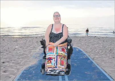  ?? CAPE BRETON POST ?? Erin MacPhee was closer to the Atlantic Ocean on Tuesday than she’s been in almost 20 years, thanks to a new ramp and special wheelchair-friendly mats that lead to the water’s edge. “Sitting here, hearing the waves hit the beach, this is home,” the...