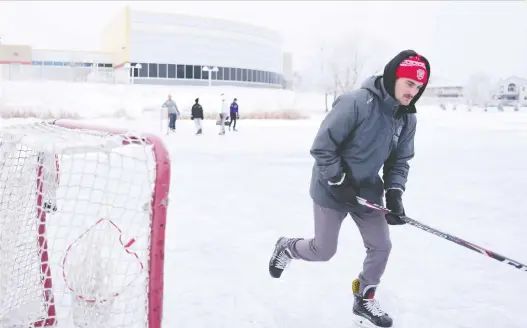  ?? MICHAEL BELL ?? Tyler Lees plays shinny on a frozen lake behind the Sandra Schmirler Centre. City officials say the ice may not yet be safe because temperatur­es have not been low enough.