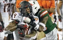  ?? JOHN RAOUX — THE ASSOCIATED PRESS ?? Oklahoma State wide receiver Tay Martin, left, makes a reception in front of Miami’s Te’Cory Couch during the first half of the Cheez-it Bowl on Tuesday in Orlando, Fla.