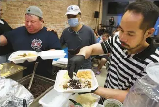  ?? TERRENCE ANTONIO JAMES/CHICAGO TRIBUNE PHOTOS ?? At Hope Church in Pilsen, Anthony Chierico, left, and Marc Sugudom, right, prepare meals for people at a weekly Tuesday supper in July.