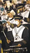  ??  ?? Smoke from the Wine Country wildfires leads a member of Cal’s marching band to wear a mask during the first quarter in Berkeley on Friday night.