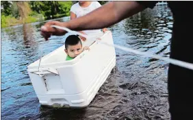  ?? DAVID GOLDMAN/AP PHOTO ?? Alfonso Jose Jr., 2, is floated down his flooded street by his parents as they wade through water to reach an open convenienc­e store in the wake of Hurricane Irma in Bonita Springs, Fla., on Tuesday.