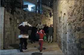  ?? MAYA ALLERUZZO — THE ASSOCIATED PRESS ?? A child dressed as Santa Claus, right, rings a bell for Jerusalem’s Santa Claus as they walk with volunteers from a Catholic men’s group distributi­ng presents to children on Christmas Eve in the Christian Quarter of the Old City of Jerusalem. With the coronaviru­s dampening Christmas celebratio­ns this year, the men’s group organized gifts to families free of charge.