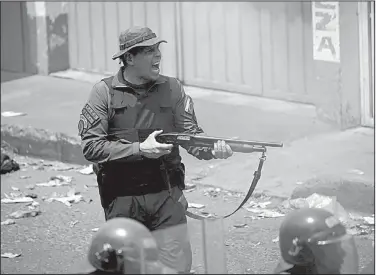  ?? AP/FERNANDO LLANO ?? An officer of Venezuela’s National Guard fires a shotgun during clashes with protesters Saturday on the border with Colombia.