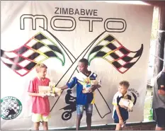  ??  ?? NUMERO UNO . . . One of Zimbabwe’s top junior motocross riders Emmanuel Bako (centre) takes the first step on the podium after coming out tops in the 65cc A Class at the end of the three-day Zimbabwe Summer Series at Donnybrook Park in Harare on Sunday...