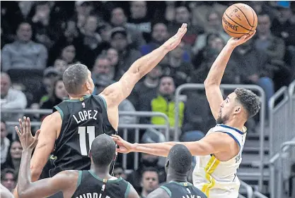  ??  ?? The Warriors’ Klay Thompson, right, shoots against the Bucks’ Brook Lopez in Milwaukee.