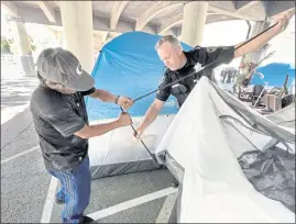  ??  ?? Gabriel Alvarez gets help setting up his new tent from San Rafael police Sgt. Carl Huber after being relocated from a homeless camp to a nearby service support area last week.