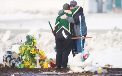  ?? CP PHOTO ?? People hug and pay their respects at a makeshift memorial at the intersecti­on of a fatal bus crash near Tisdale, Sask., on Monday.