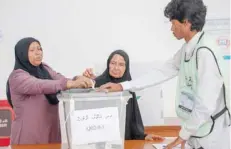  ?? (Below) — AFP ?? A woman (L) assists her elderly mother to cast her ballot at a polling station in Male on Sunday. President Abdulla Yameen (R) arrives at a polling station and Opposition candidate Ibrahim Mohamed Solih casts his vote.