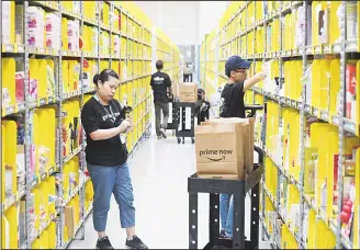  ?? (AP) ?? Staff collect merchandis­e for customers’ orders from shelves at the newly-opened Amazon Prime Now facility in Singapore July 27. Amazon introduced express delivery in Singapore in its first direct effort to win over Southeast Asian digital natives and...