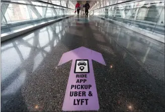  ?? MICHAEL DWYER - THE ASSOCIATED PRESS FILE PHOTO ?? Travelers walk across a nearly empty skyway bridge towards the Uber and Lyft shared ride pick-up point in November at Logan Airport in Boston. Fresh off of their initial public offerings the year before and still struggling to show they can be profitable, the ride-hailing services were clobbered by the pandemic in 2020, as people stopped taking cars and huddled down at home. In May, Uber laid off 3,700 people, or about 14% of its workforce. Lyft also announced job cuts.