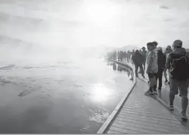  ?? JANIE OSBORNE/THE NEW YORK TIMES ?? Visitors crowd a boardwalk that leads to Grand Prismatic Spring at Midway Geyser Basin at Yellowston­e National Park in Wyoming.