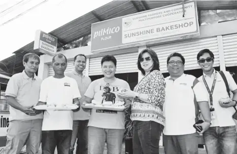 ?? PR ?? With a big smile on her face, Ate Nora (center) proudly showcases her baked goods as she poses with representa­tives of the Aboitiz Group.