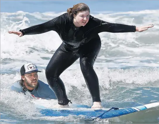  ?? Mel Melcon Los Angeles Times ?? NIKKI MORAN, a beginning surfer from England, is guided by Peter Paris, a teacher for GoSurfLA.com, one of several area surfing schools, at Venice Beach.