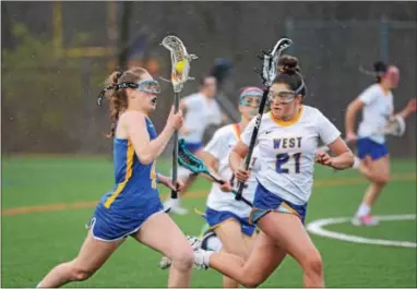  ?? MICHAEL REEVES — FOR DIGITAL FIRST MEDIA ?? Downingtow­n East’s Allison Sheridan runs alongside West’s Tabitha Rodrigues during Thursday night’s Ches-Mont girls lacrosse game.