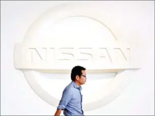  ?? TORU YAMANAKA/AFP ?? A man walks past a logo of Japan’s automaker Nissan Motor at a showroom in Yokohama on July 27. Scandal-hit Nissan said yesterday it had downgraded its forecast for annual operating profit, after an inspection scandal in its home market Japan.