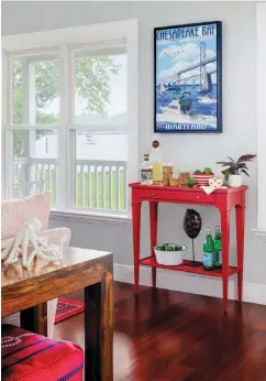  ??  ?? |BELOW, RIGHT| BAR NONE. A red-painted Woodbridge side table doubles as a bar below a framed vintage Chesapeake Bay poster.