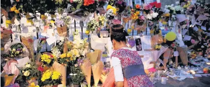  ??  ?? > A member of the public looks at tributes outside Notting Hill Methodist Church, near Grenfell Tower, London