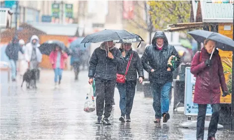  ?? ?? Shoppers on Perth High Street brave the atrocious weather.