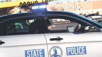  ?? — AFP photo ?? A Virginia State Police officer watches the police line set up at the site of the fatal shooting at the Chesapeake Walmart Supercentr­e in Virginia.