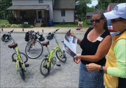  ?? RICHARD PAYERCHIN — THE MORNING JOURNAL ?? Catherine Girves, executive director of Yay Bikes!, shows photos of various styles of bike racks to Kim Haney, medical health technology instructor for Marion L. Steele High School in Amherst on. They discussed cycling before on an explorator­y ride...