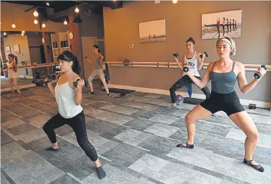  ??  ?? Isabella Uhl, right, is joined by four other participan­ts in a Barre Express class at Barre Forte. Classes are limited to 25% of capacity for now. Some customers are opting to join classes online.