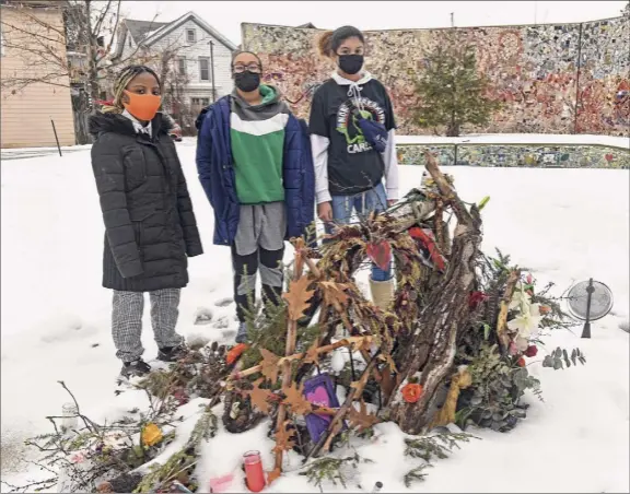  ?? Photos by Lori Van Buren / Times Union ?? Troy residents Genesis Cooper, 15, left, Shansaniqu­e Pollack, 15, and Gabby Espada, 14, stand in back of an altar for the victims of violence and those who died from COVID-19. The site is in a lot near the Sanctuary for Independen­t Media.