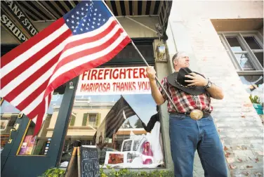  ?? Noah Berger / Associated Press ?? Charles Phillips waits, along with most of the Sierra foothills town of Mariposa, for the procession carrying the body of firefighte­r Braden Varney to pass by at the junction of highways 49 and 140.